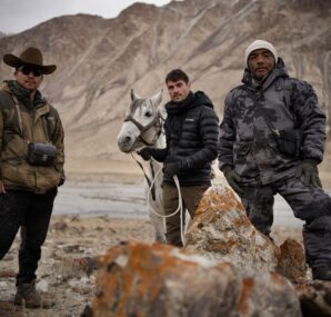 Dan with a camera next to large wall of rocks