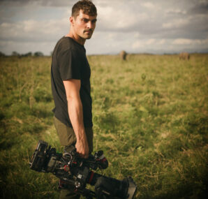 Dan with a camera next to large wall of rocks