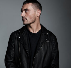 Dan with a camera next to large wall of rocks