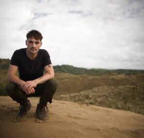 Dan with a camera next to large wall of rocks