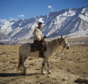 Dan with a camera next to large wall of rocks