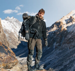Dan with a camera next to large wall of rocks