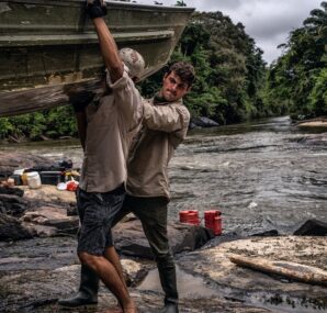 Dan with a camera next to large wall of rocks